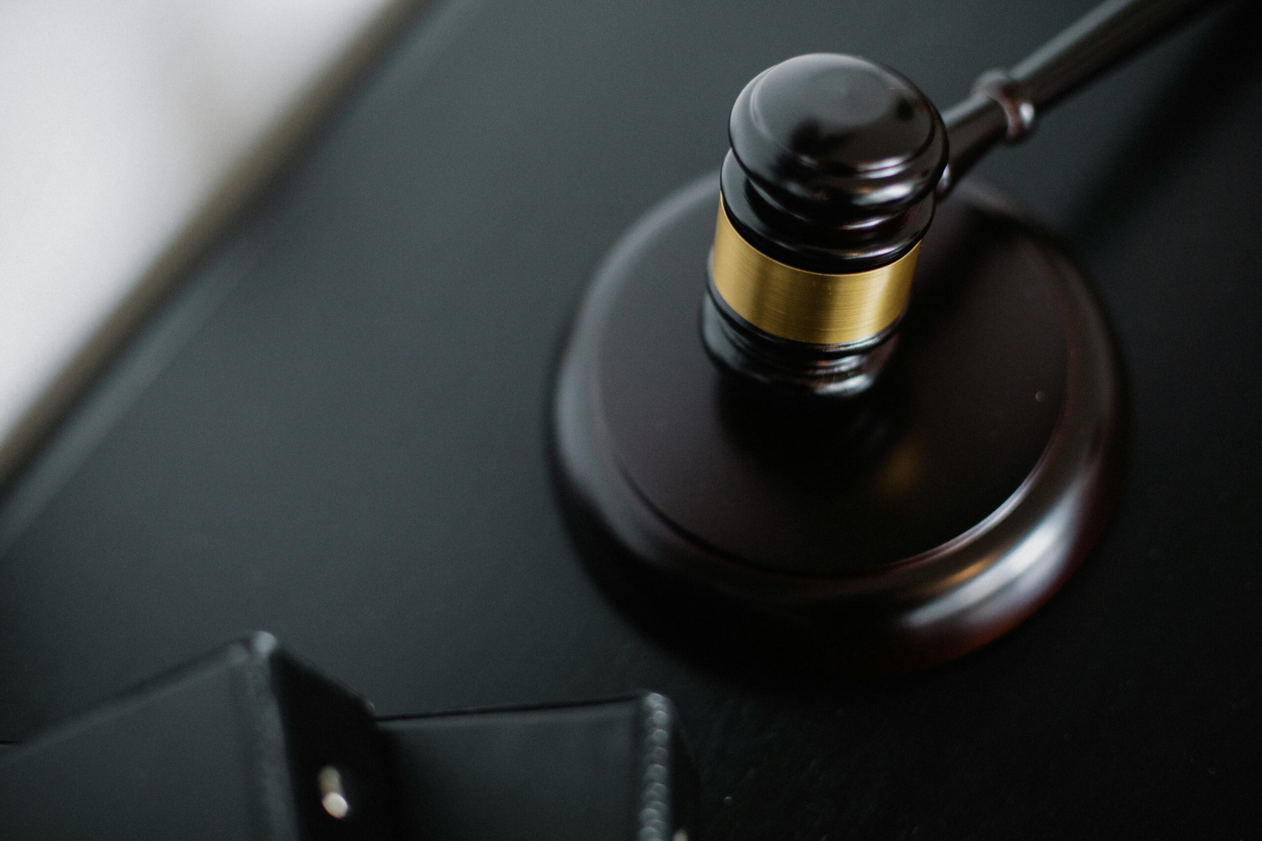 Close-up of a wooden judge's gavel on a black desk, symbolizing justice and law.